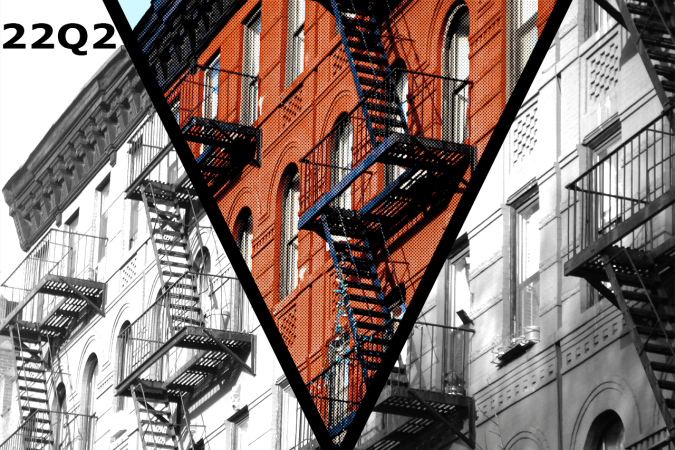The side of a building with many fire escapes. The photo appears in black and white with a V-shaped center section in bright, comic-book style color, the building vibrant orange-red. 